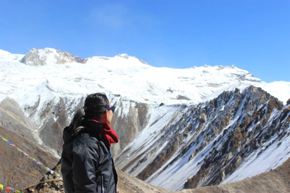A woman looks behind her at a vast mountains valley.