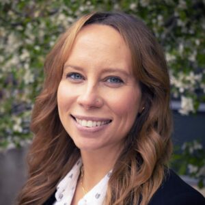 Headshot of a woman with a white blouse and black sweater.