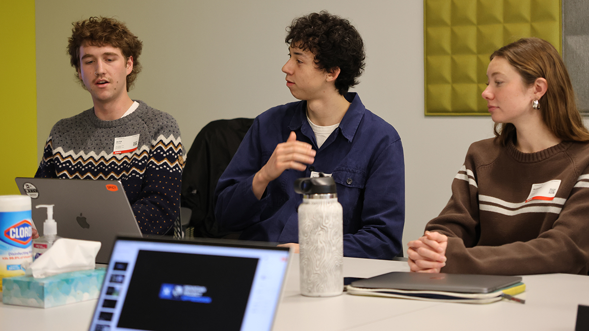Three people present findings around a conference table.