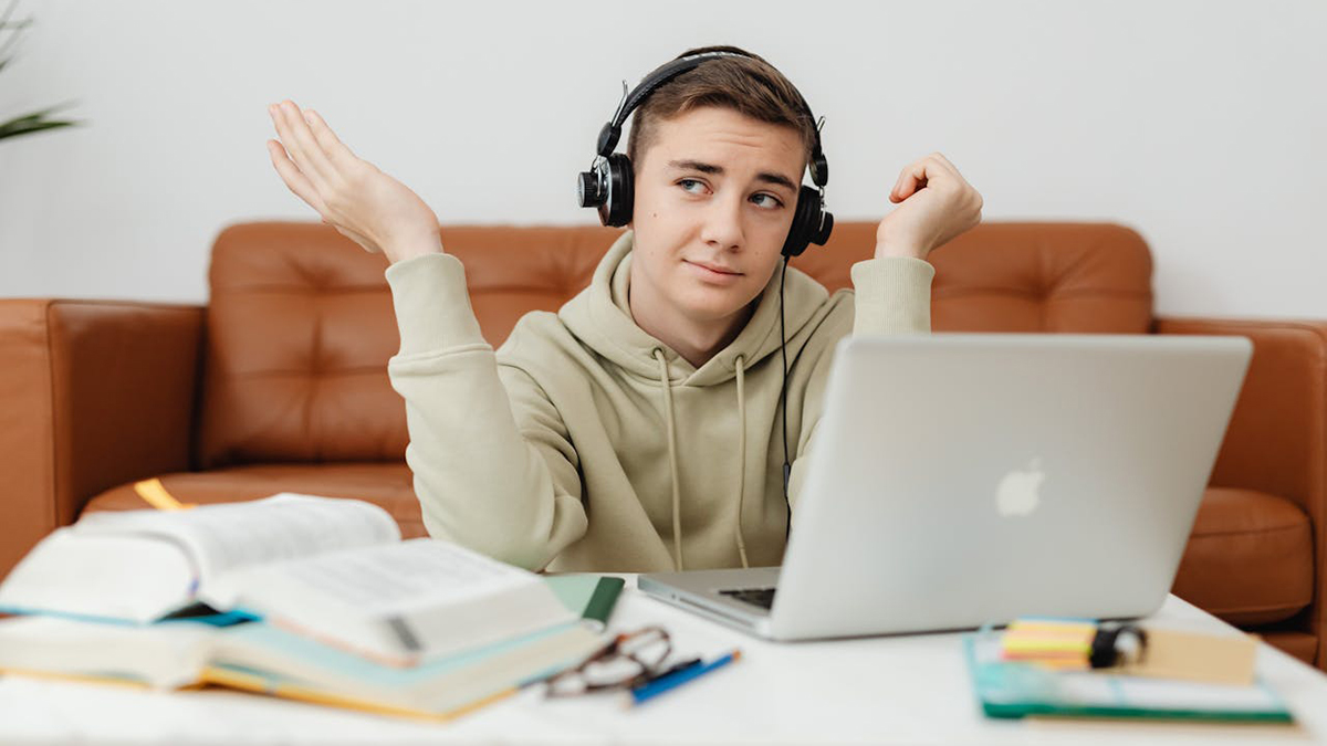A student wears headphones and works on a laptop